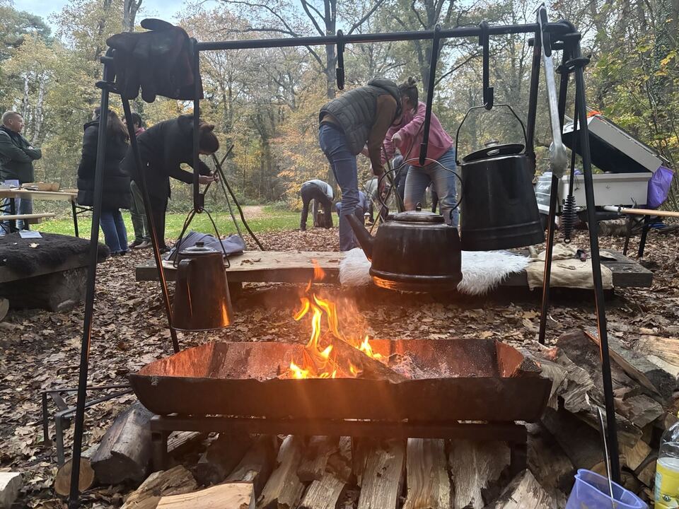 Team rond het kampvuur tijdens een bushcraft bedrijfsuitje in het bos