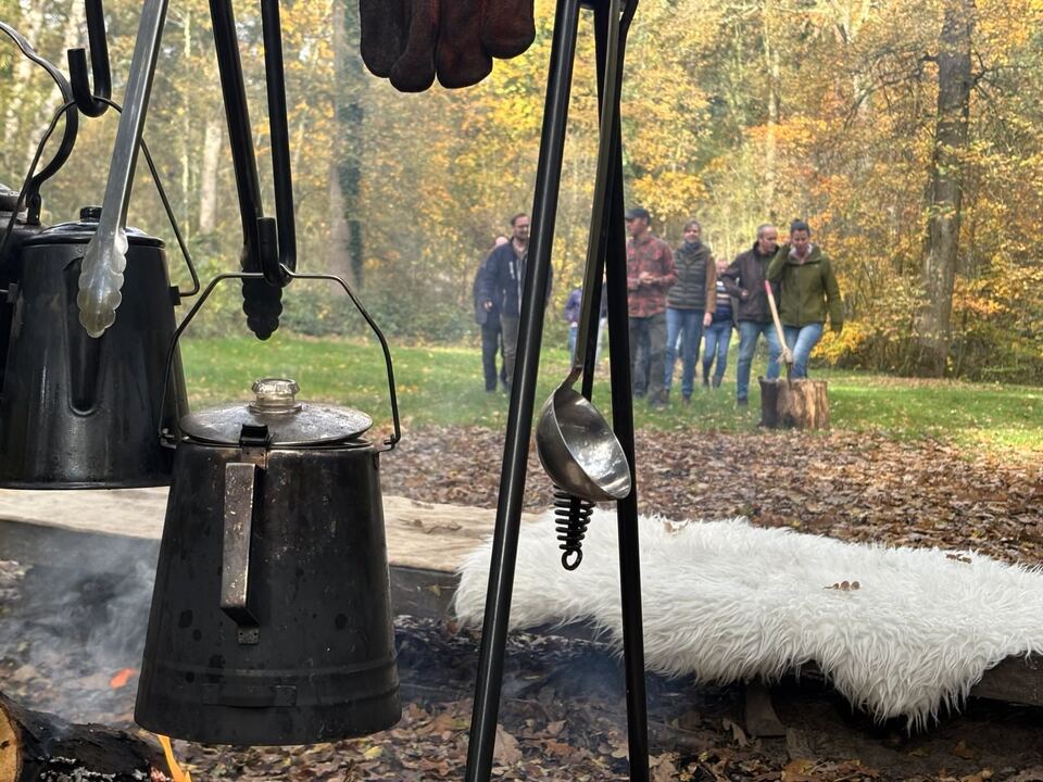 Kookopstelling met ketels boven het vuur en team op de achtergrond
